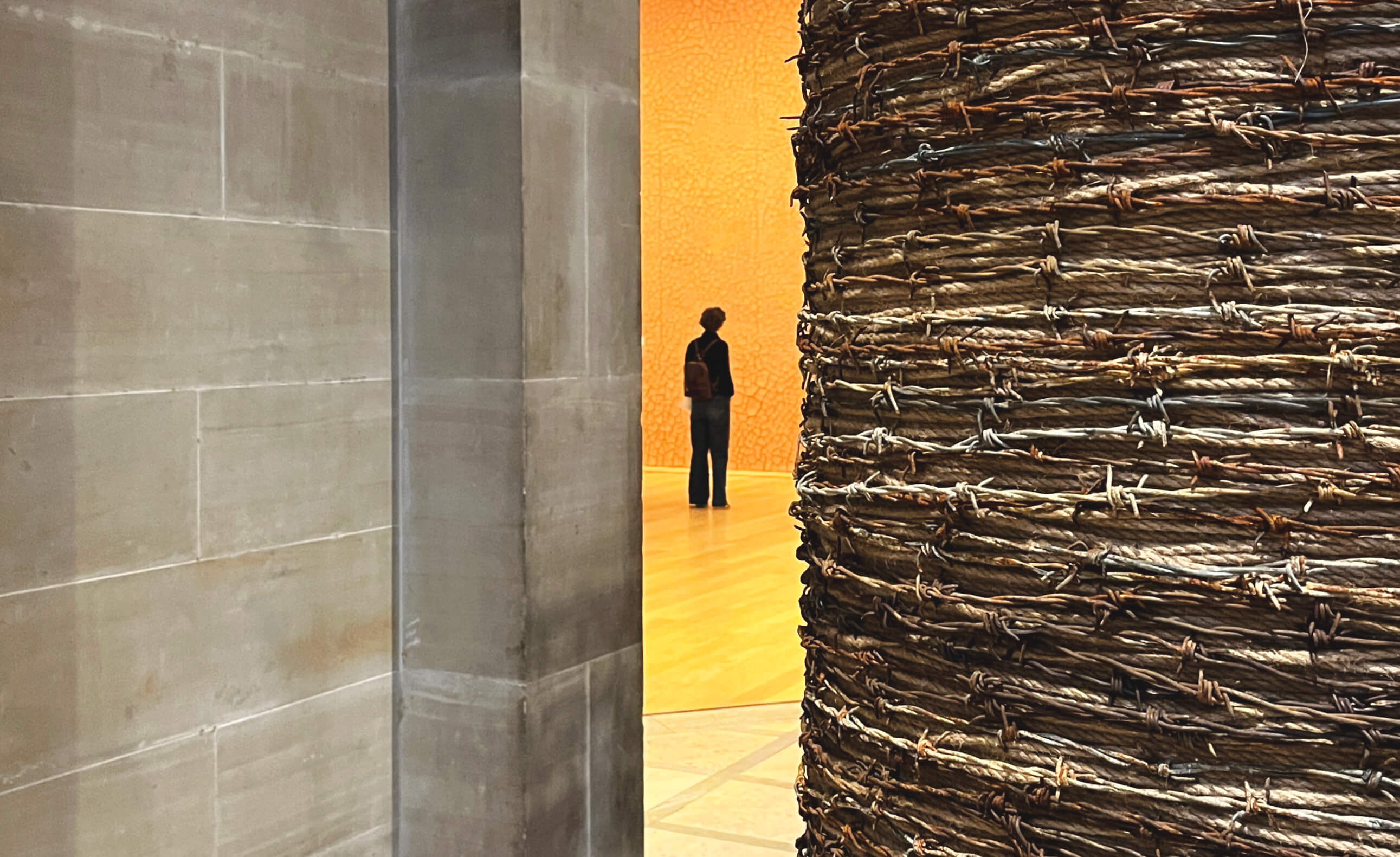 A visitor looking at Andy Goldsworthy’s Red Wall, with the artist’s barbed wire Fence in the foreground.